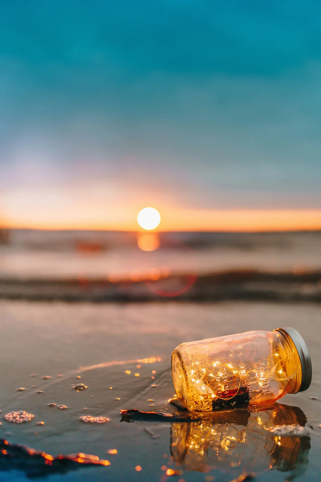 Jar with lights on a beach at sunset